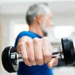 Un homme âgé exerce les muscles de l'épaule à l'aide d'un haltère, en se concentrant attentivement